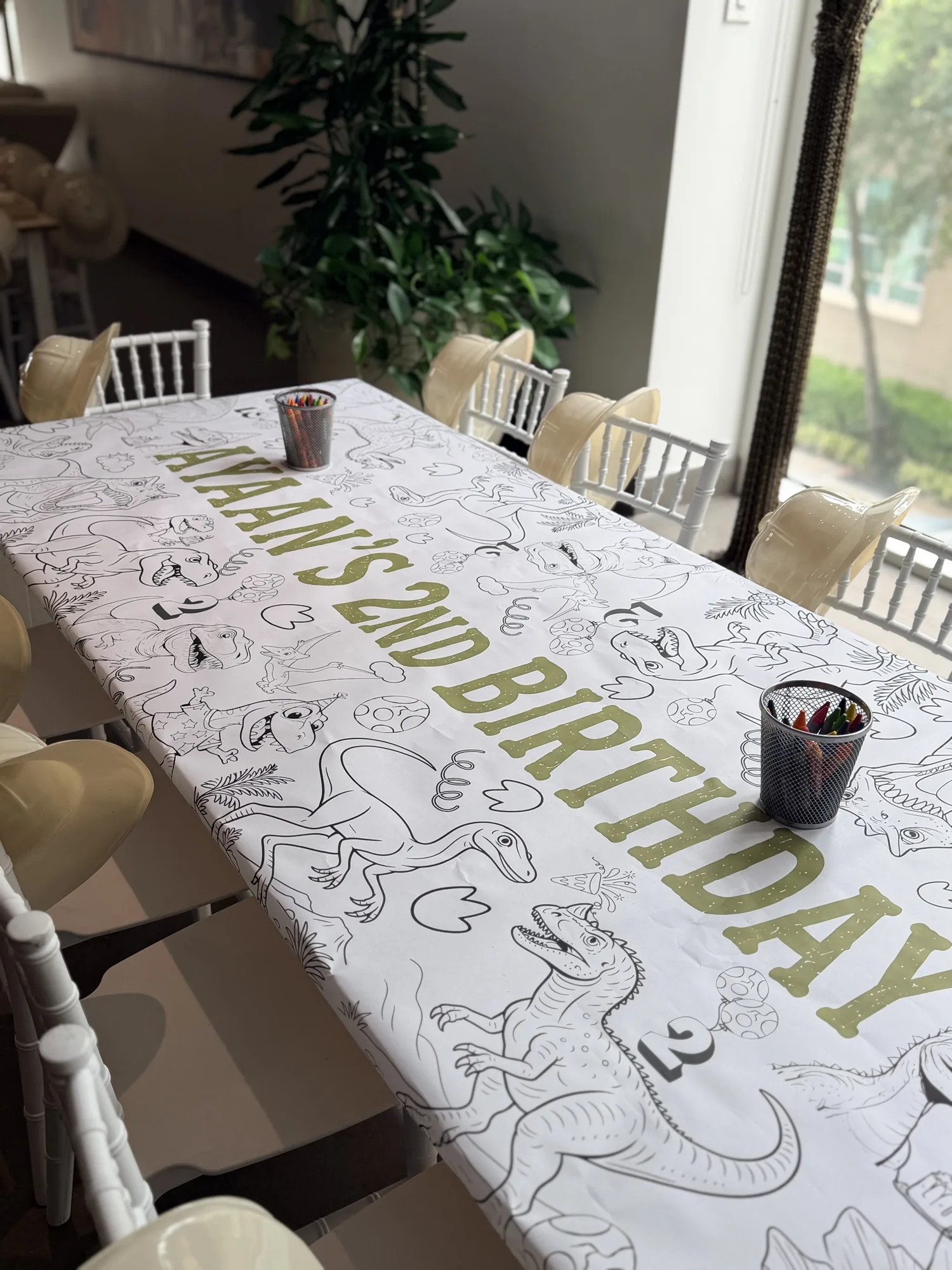Kids coloring table with chiavari chairs and a personalized dinosaur banner