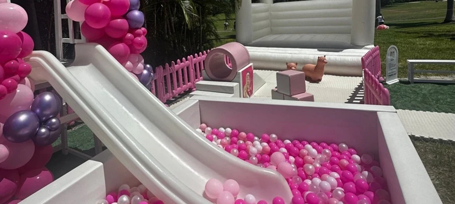 Pink ball pit with a white slide and balloon installation at a Miami birthday party